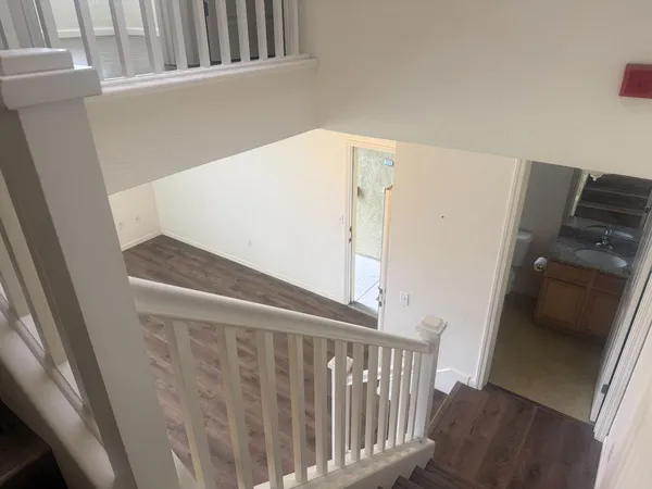 a view of stairs and an empty room with wooden floor
