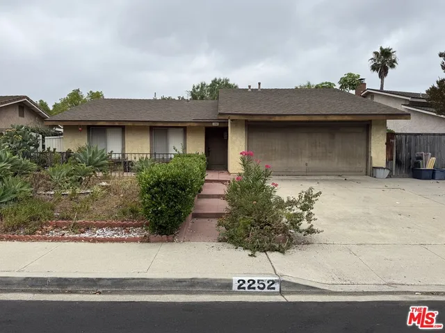 a front view of a house with garage and plants