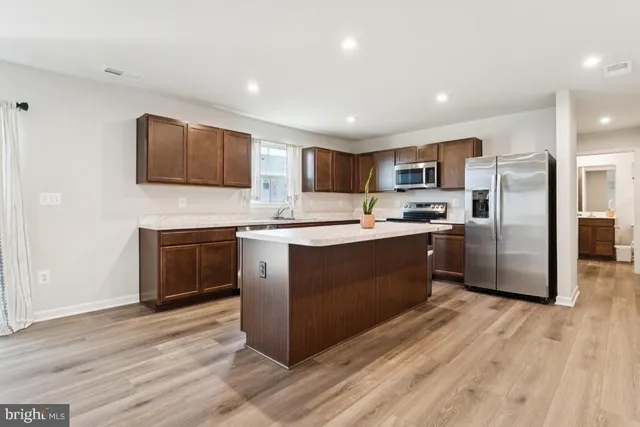 a kitchen with stainless steel appliances kitchen island granite countertop a stove a sink dishwasher a refrigerator and a oven with wooden floor