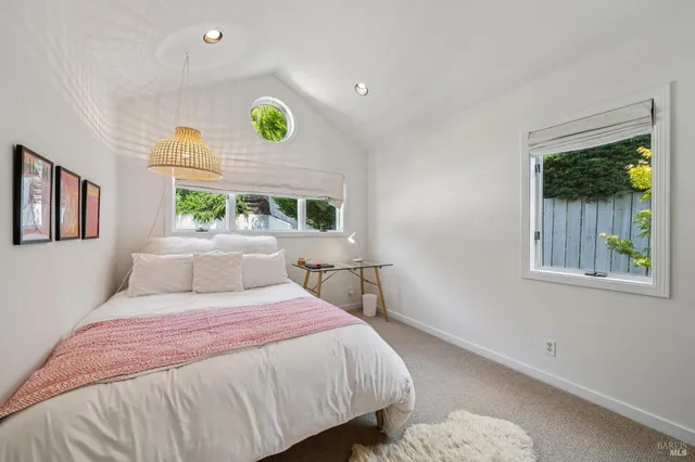 a bedroom with a bed window and mirror