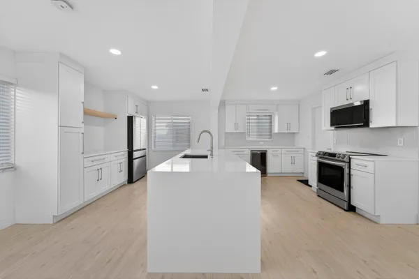 a large white kitchen with cabinets and a stove top oven