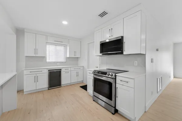 a kitchen with stainless steel appliances white cabinets and a stove top oven