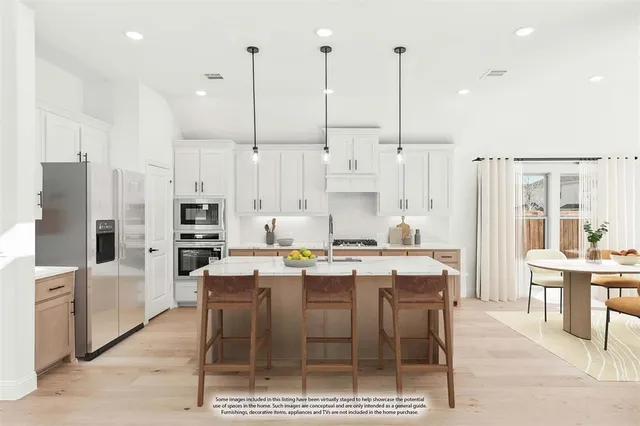 a kitchen with stainless steel appliances kitchen island granite countertop a table chairs stove and white cabinets