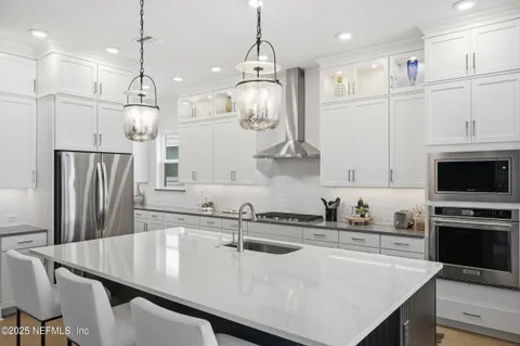 a kitchen with stainless steel appliances granite countertop a sink a stove and a refrigerator