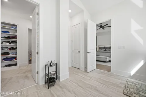 wooden floor and view of bathroom with walk in closet