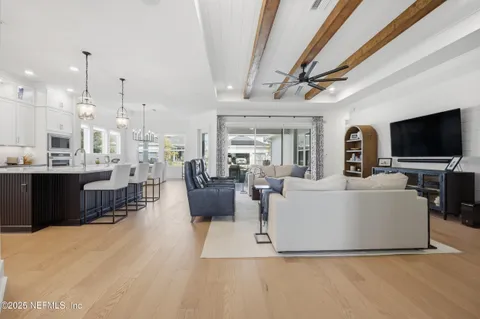 a living room with furniture a flat screen tv and kitchen view