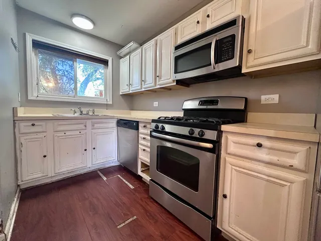 a kitchen with stainless steel appliances white cabinets and a stove top oven