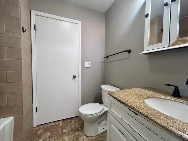 a bathroom with a granite countertop toilet and a sink