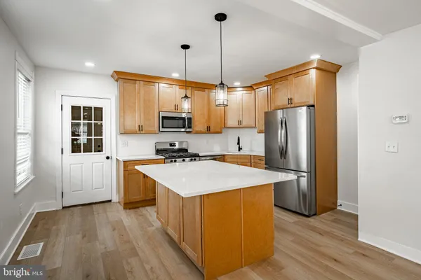 a kitchen with kitchen island a sink appliances a counter space and a window