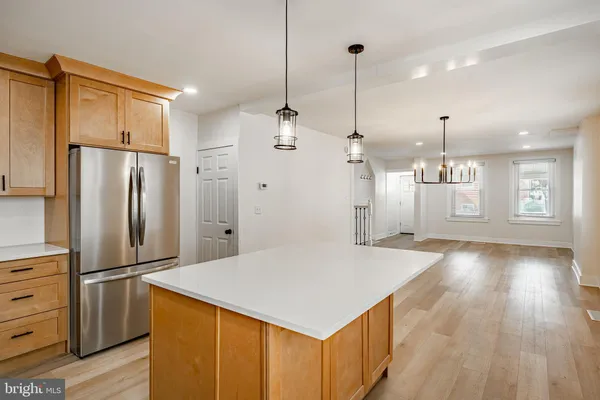 a kitchen that has a refrigerator a stove and white cabinets with wooden floor