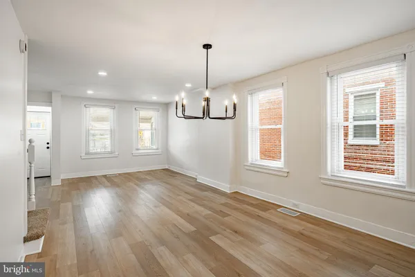 a view of an empty room with wooden floor and windows
