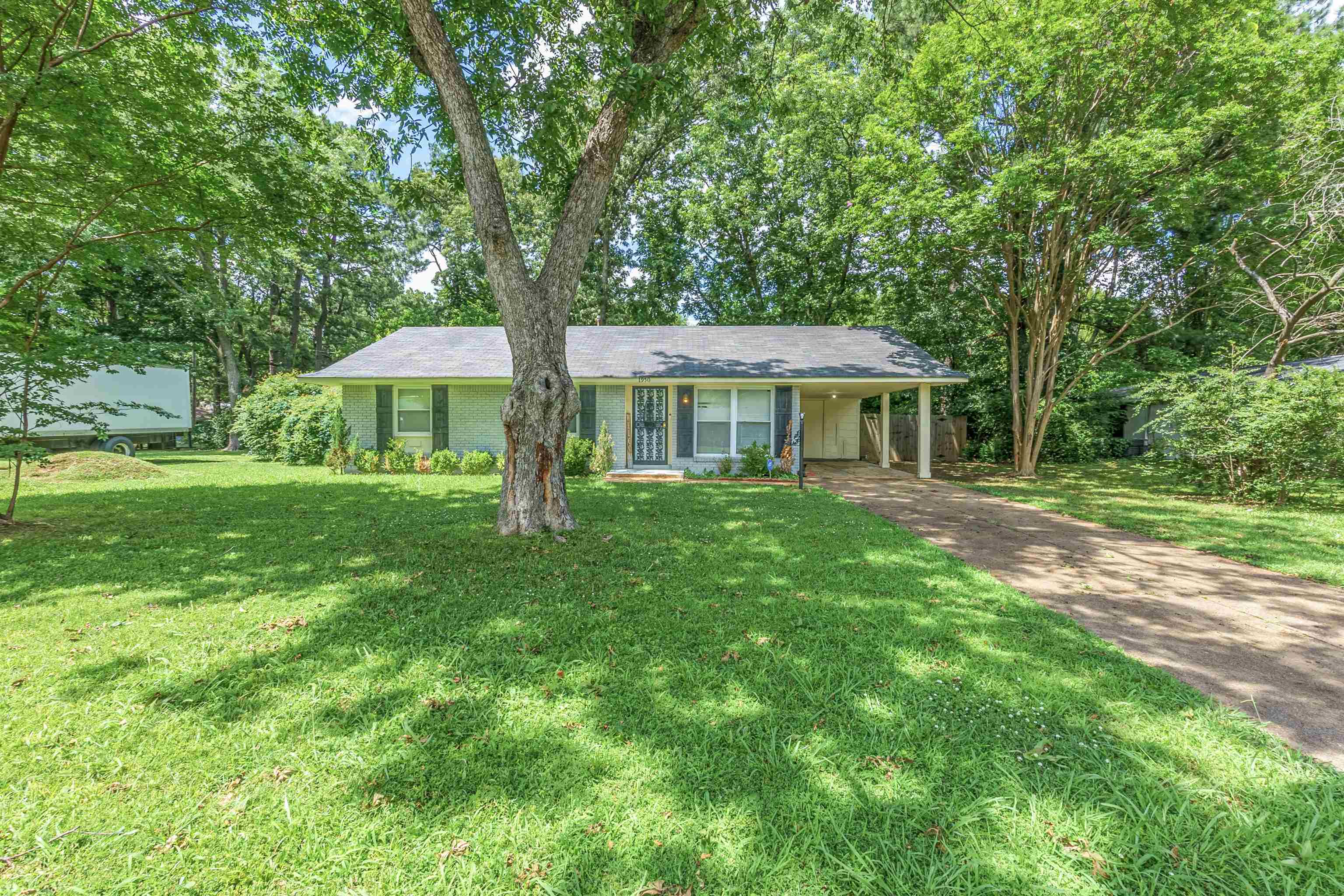 Ranch-style home featuring driveway, a front lawn, a porch, and an attached carport