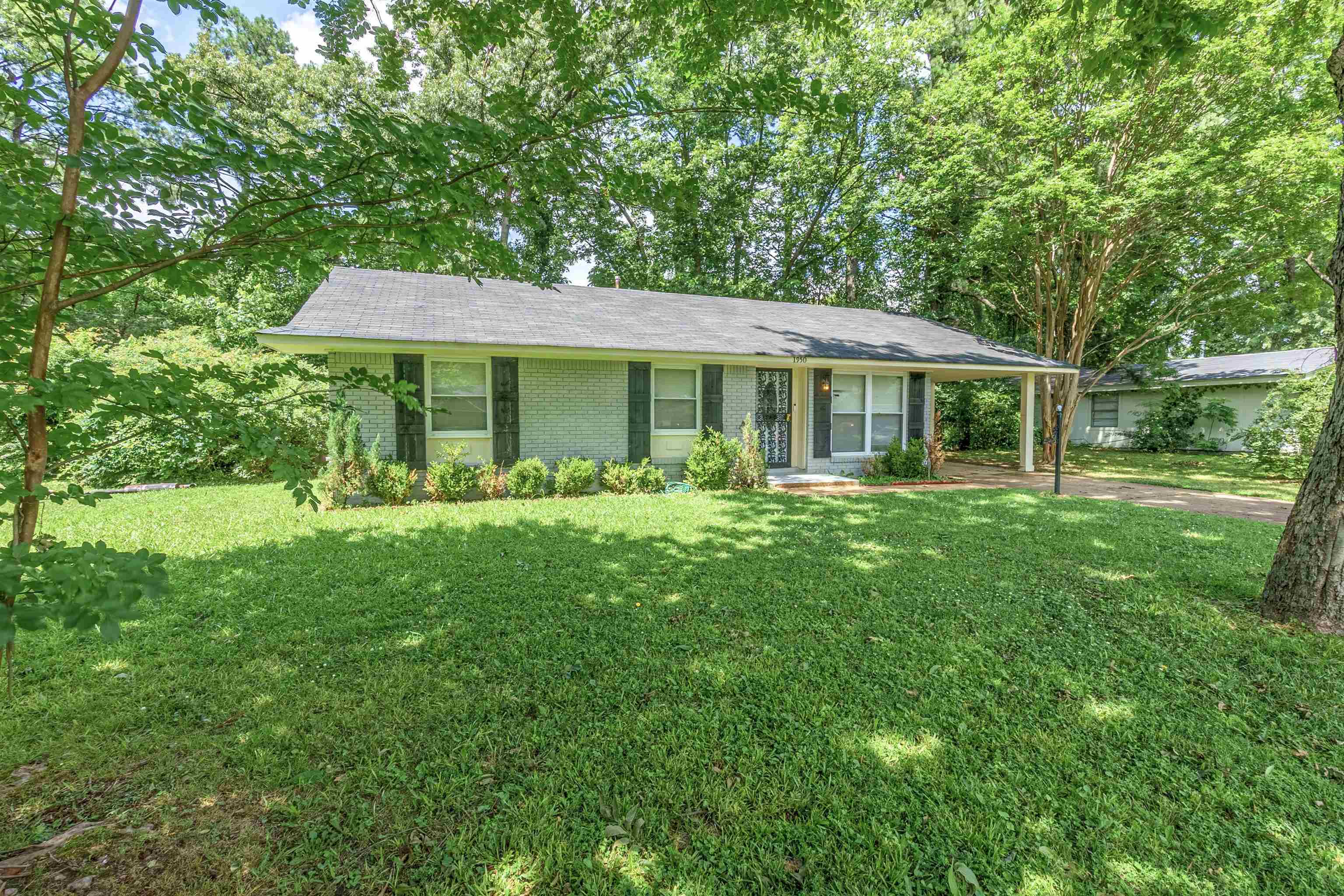 Ranch-style house featuring a front lawn, brick siding, driveway, and an attached carport