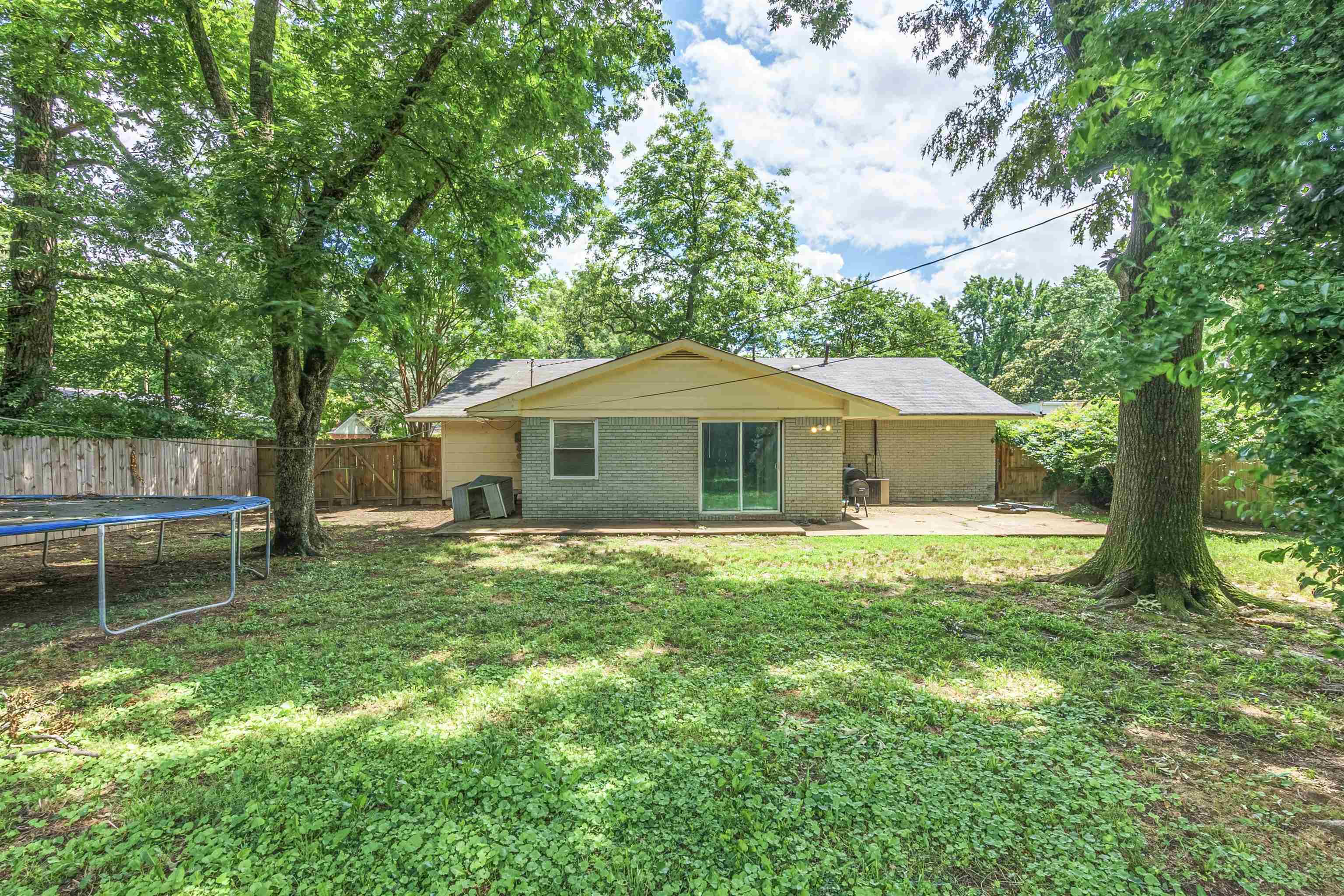 1950 Victoria Road Memphis, TN 38116 - Photo 23 of 25 Rear view of house featuring a patio area, a fenced backyard, brick siding, and a trampoline