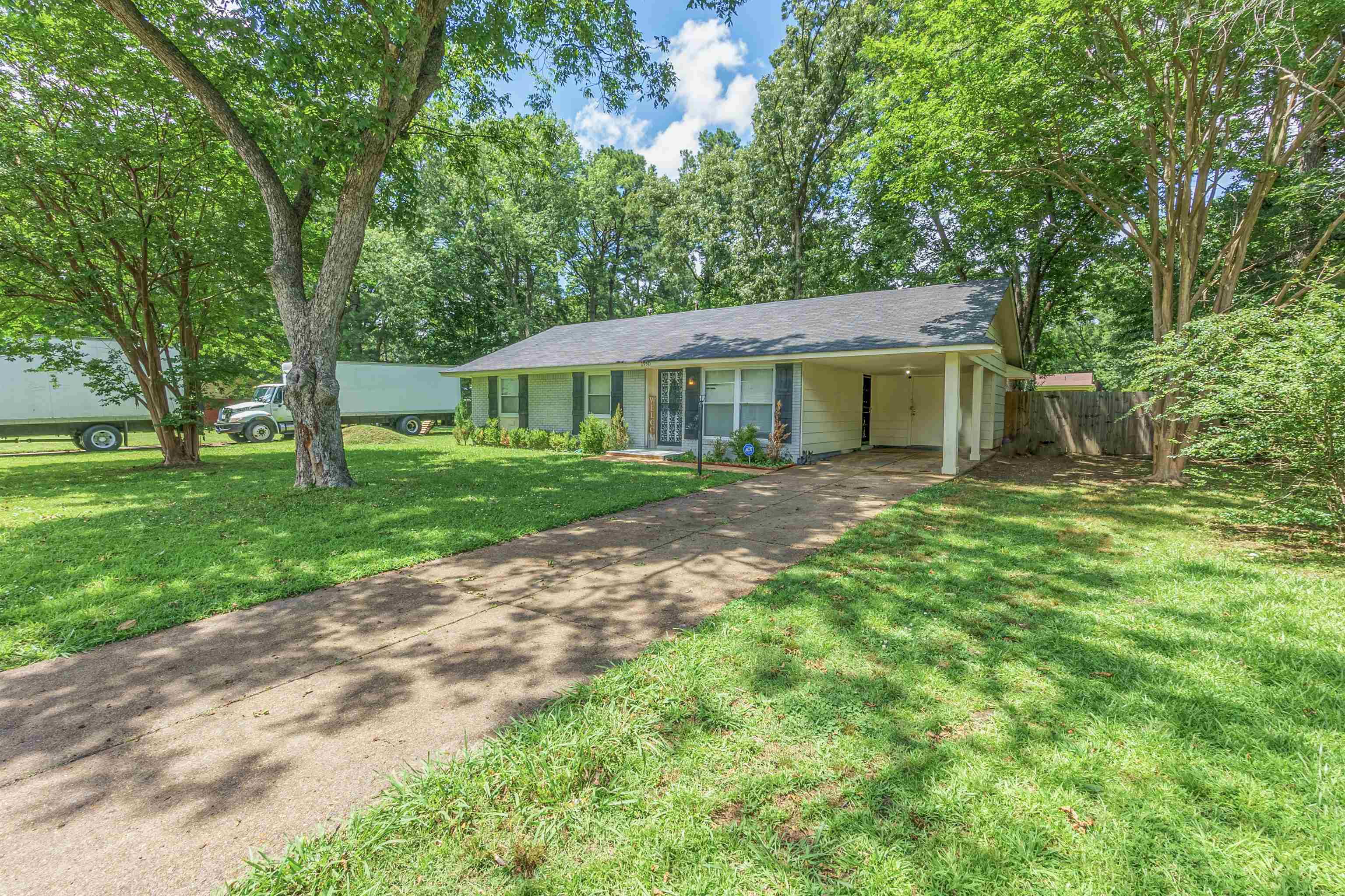 Ranch-style home featuring concrete driveway and a carport