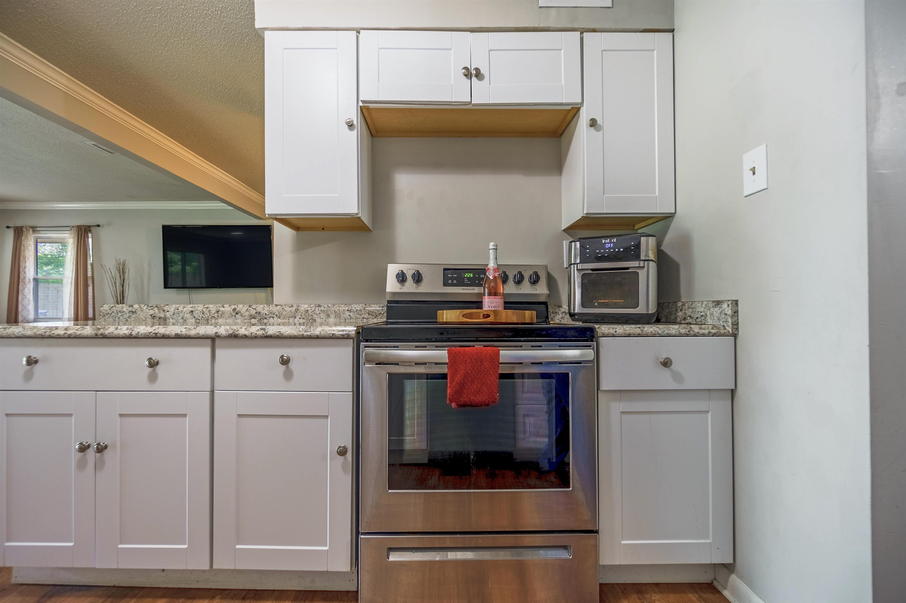Kitchen featuring white cabinetry, stainless steel electric range oven, a textured ceiling, ornamental molding, and light stone counters