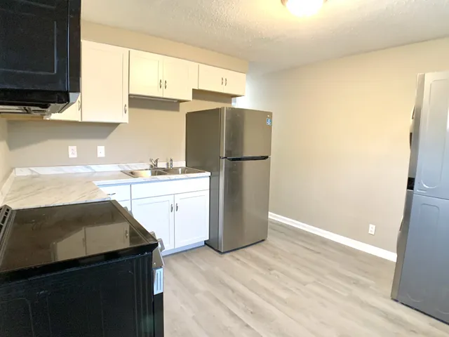 a kitchen with a sink a stove a refrigerator and cabinets