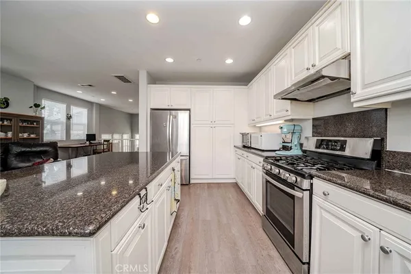 a large kitchen with stainless steel appliances granite countertop a stove a sink and a refrigerator