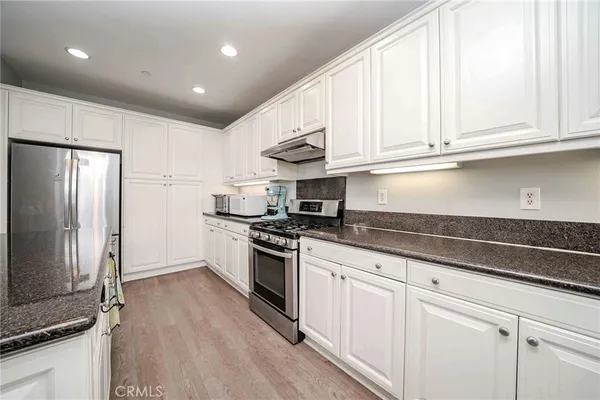 a kitchen with granite countertop white cabinets and stainless steel appliances