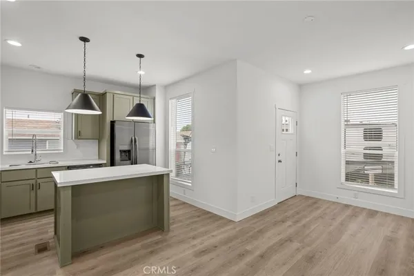 a kitchen with stainless steel appliances granite countertop a sink a stove a refrigerator and island with wooden floor