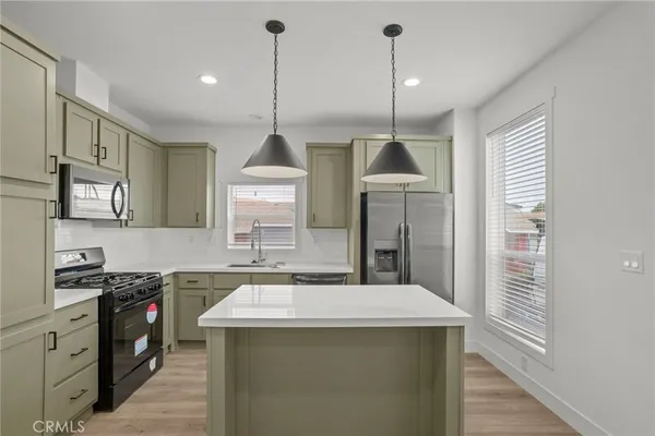 a kitchen with stainless steel appliances granite countertop a sink a stove and a wooden floors