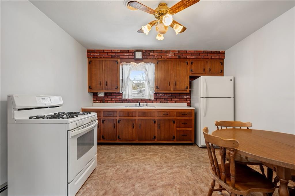 It includes a white gas stove and refrigerator, ample countertop space, and a window above the sink that keeps the room bright.