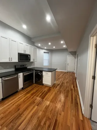a large kitchen with stainless steel appliances granite countertop a stove and a wooden floors