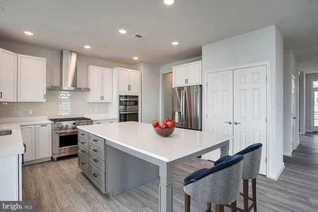 a open kitchen with stainless steel appliances granite countertop a stove a sink dishwasher and a dining table with wooden floor