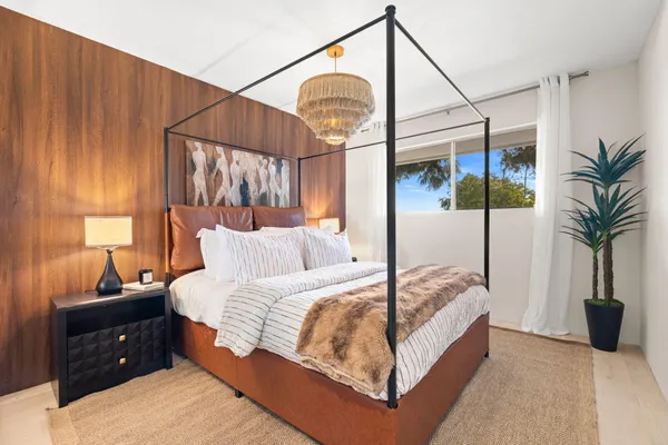 a bedroom with a bed a potted plant and a window