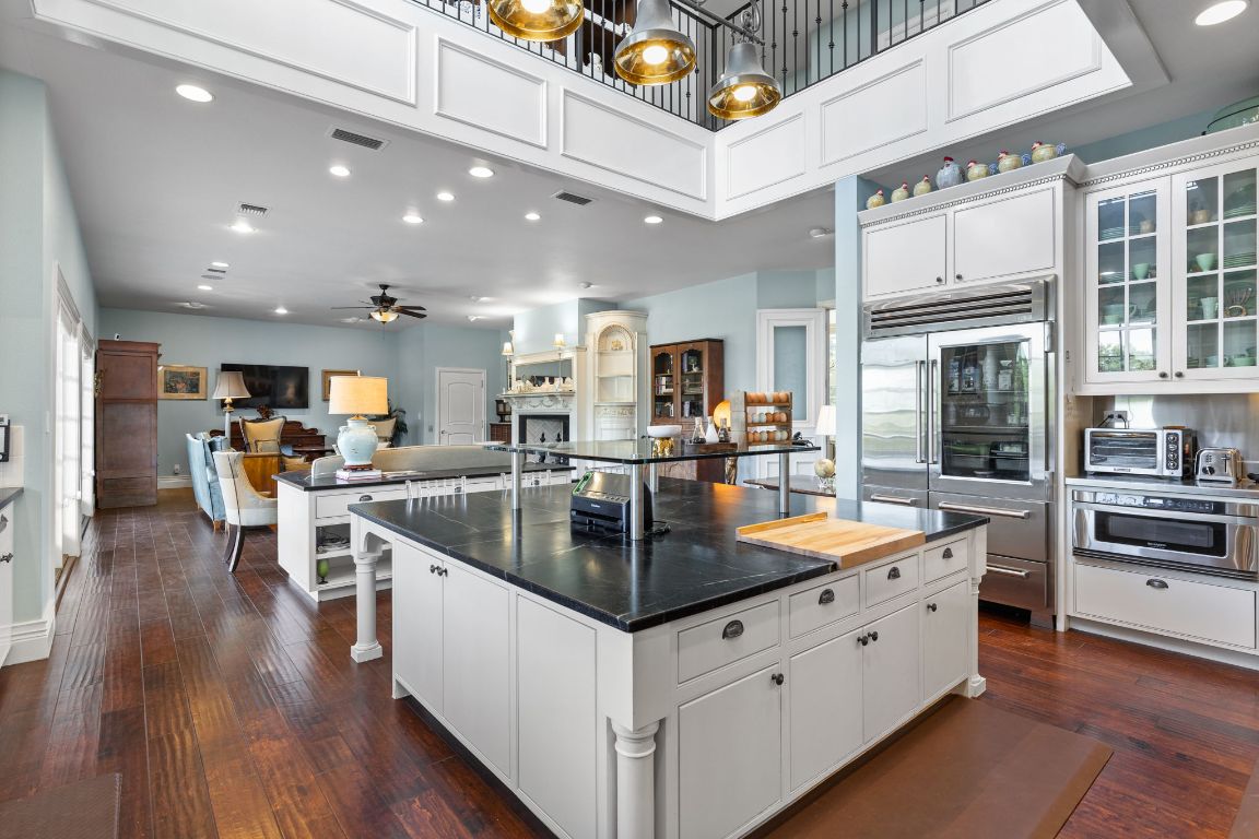999 Schwarzlose Road New Braunfels, TX 78130 - Photo 8 of 39 a kitchen with stainless steel appliances kitchen island granite countertop a stove and a wooden floors