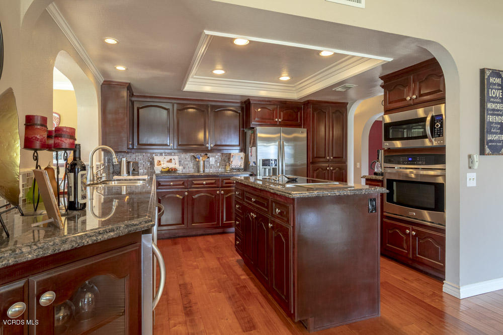 1795 Rambling Road Simi Valley, CA 93065 - Photo 13 of 60 a kitchen with stainless steel appliances granite countertop a refrigerator a sink dishwasher a stove and a dining table with wooden floor