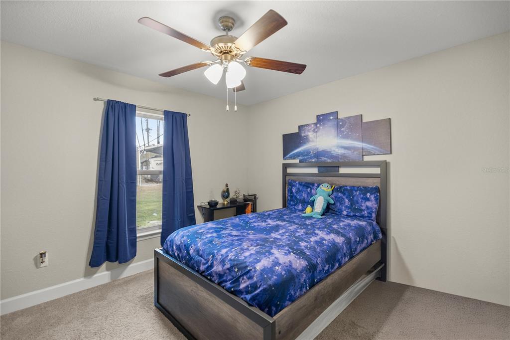 9609 Southwest 40th Terrace Ocala, FL 34476 - Photo 21 of 28 a bedroom with a large bed and a chandelier