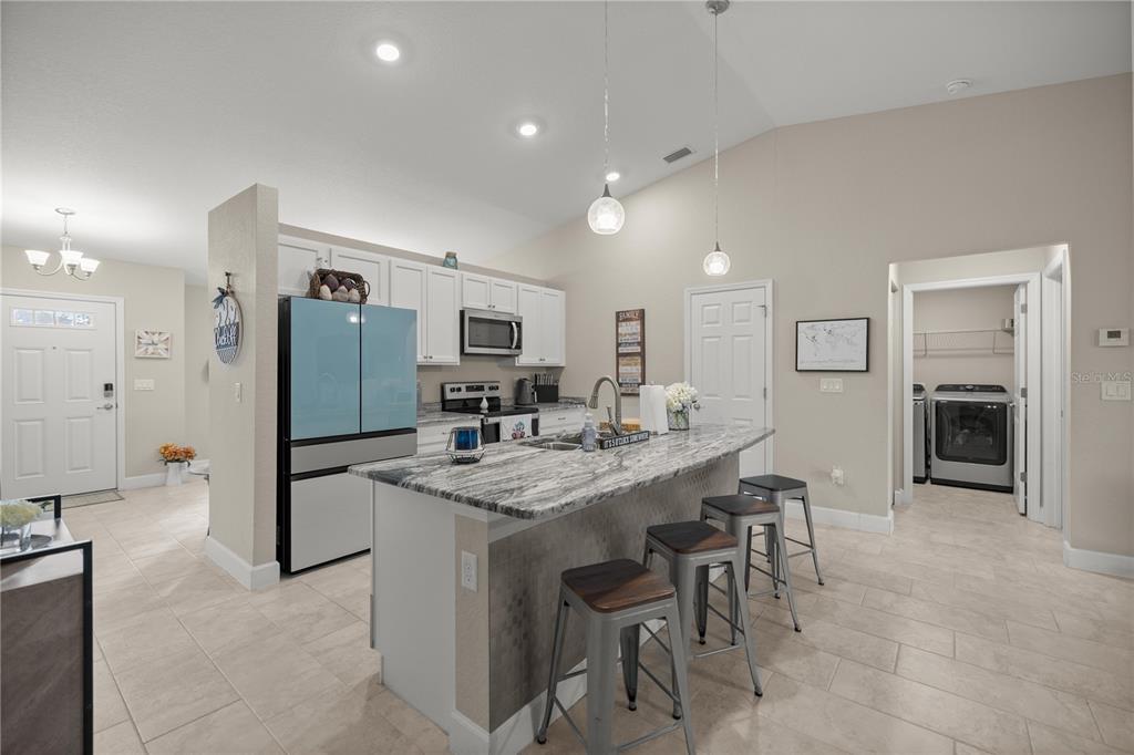 9609 Southwest 40th Terrace Ocala, FL 34476 - Photo 8 of 28 a kitchen with stainless steel appliances kitchen island granite countertop a refrigerator a stove a sink a dining table and chairs