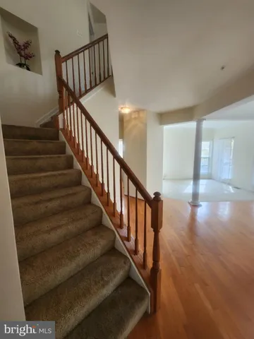 a view of staircase with lots of frames on wall and wooden floor