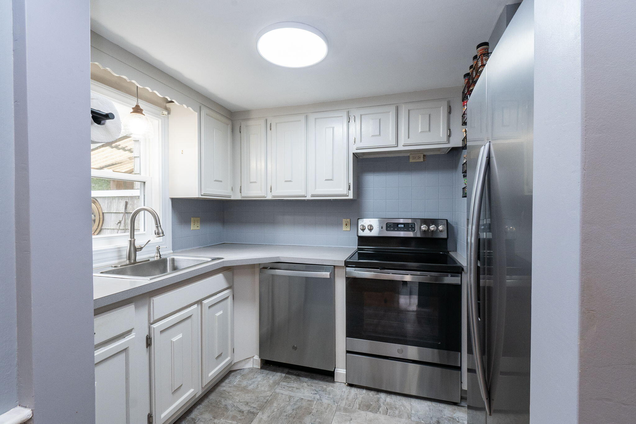 102 Sea Street Dennis Port, MA 02639 - Photo 12 of 40 a kitchen with white cabinets and stainless steel appliances