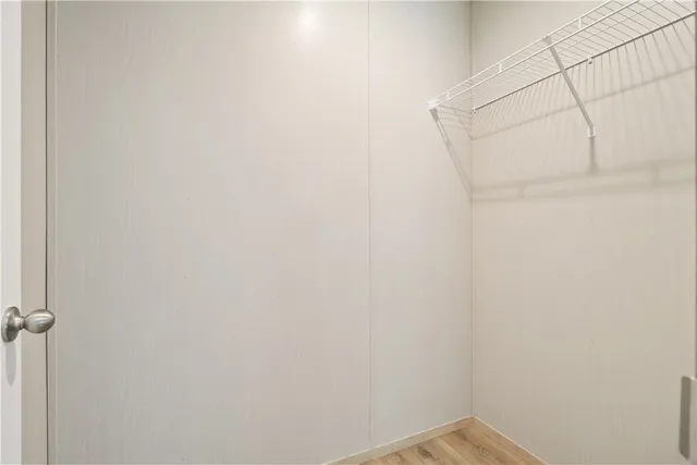 a view of an empty room with wooden floor and closet