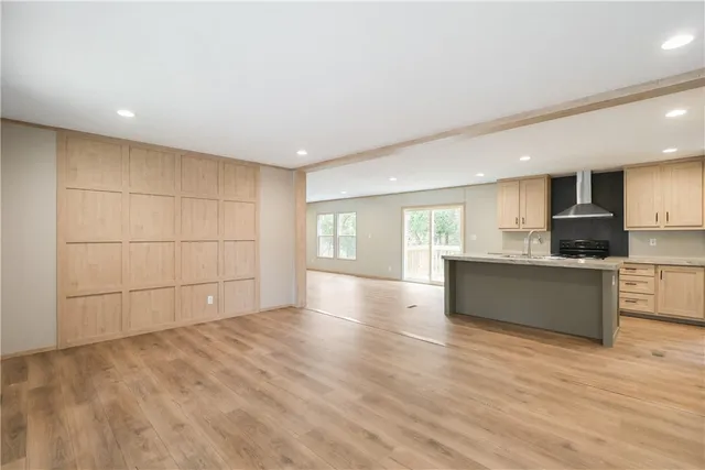 a view of an empty room with a kitchen and a window