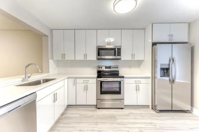 a kitchen with cabinets stainless steel appliances and a sink