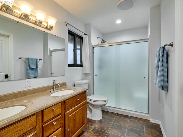 a bathroom with a double vanity sink toilet and shower