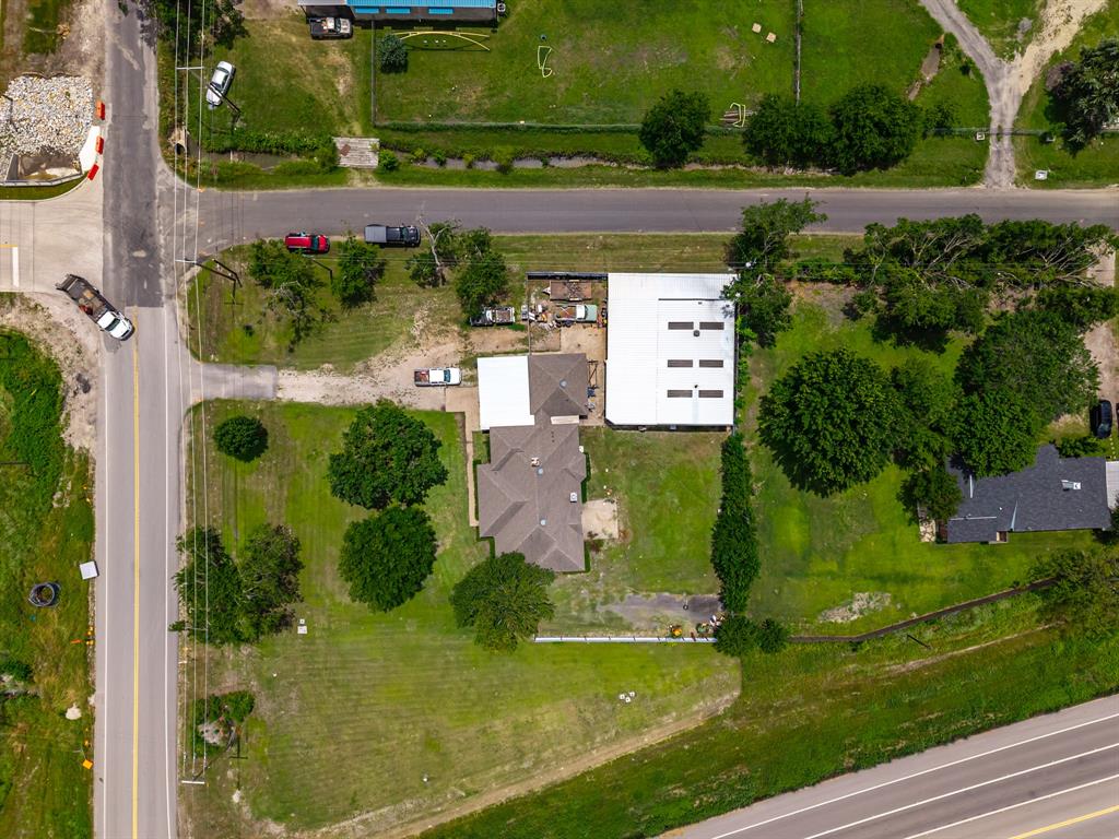 601 Houston School Road Red Oak, TX 75154 - Photo 22 of 32 Expansive property with a gabled roof residence, a large auxiliary building with a metal roof, and mature trees across a verdant lawn