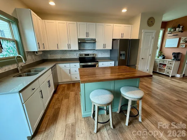 a kitchen with stainless steel appliances granite countertop a sink a stove a refrigerator cabinets and chairs