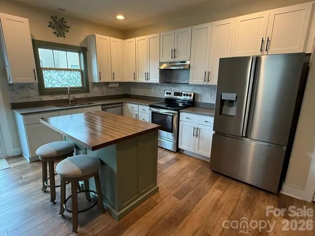a kitchen with stainless steel appliances a dining table chairs refrigerator and sink