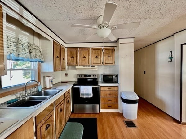10 St James Circle Hudson, MA 01749 - Photo 3 of 14 a kitchen with stainless steel appliances a sink a stove a refrigerator cabinets and a dining table with wooden floor