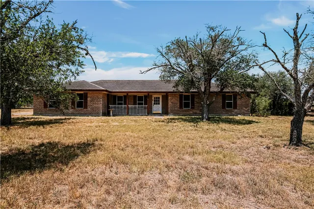 a backyard of a house with large trees and brick wall