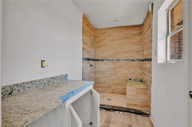 a bathroom with a granite countertop shower sink and mirror