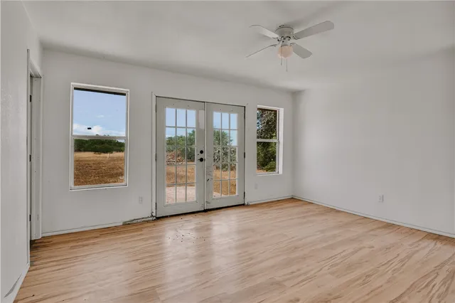 a view of an empty room with a window and wooden floor