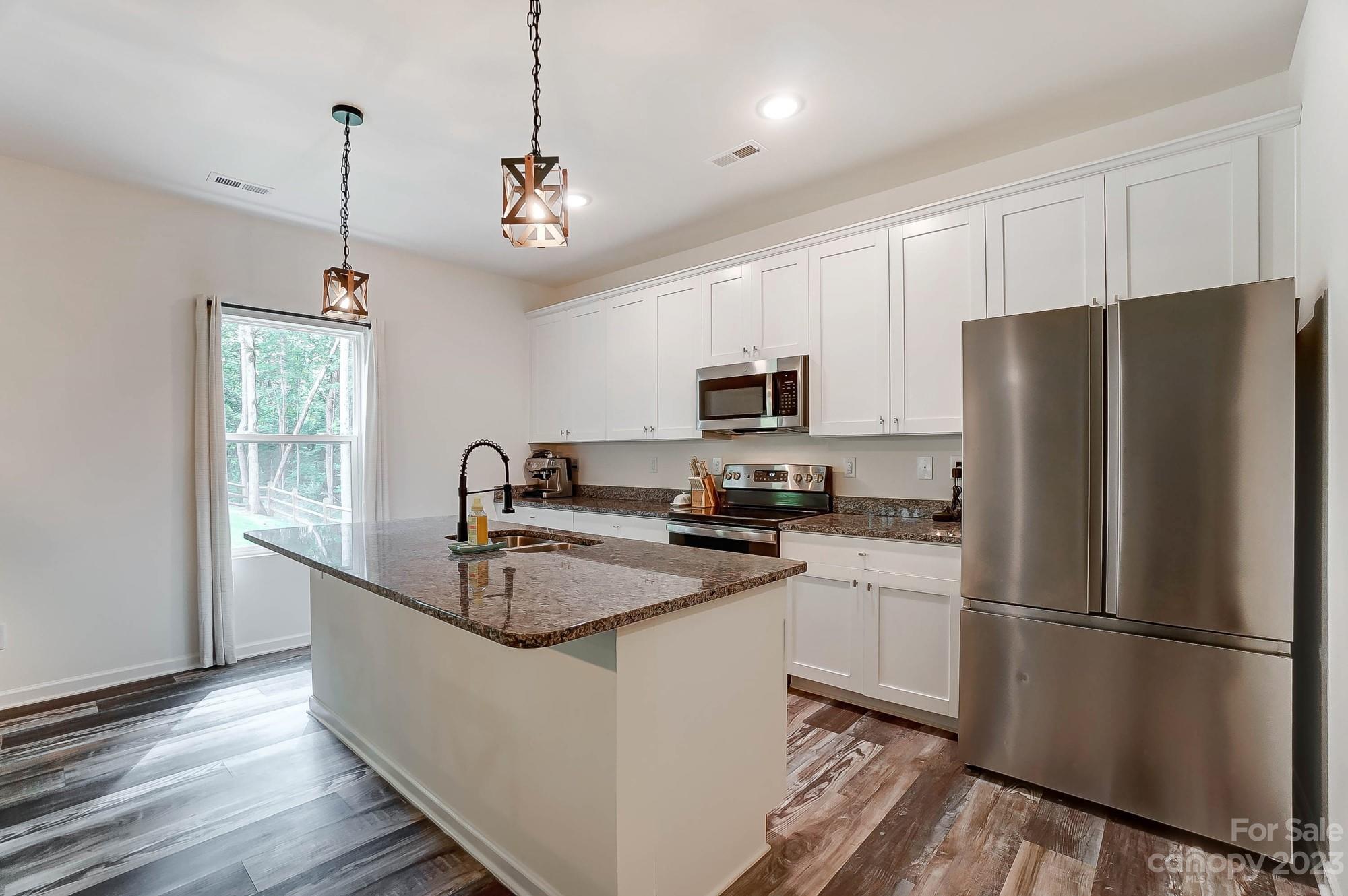 164 Mill Creek Road Iron Station, NC 28080 - Photo 15 of 48 a kitchen with stainless steel appliances granite countertop a refrigerator a sink dishwasher a oven with white cabinets and wooden floor