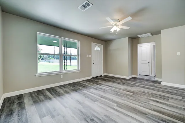 a view of an empty room with window and wooden floor