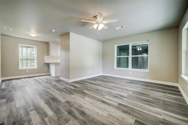 a view of an empty room with a window and wooden floor