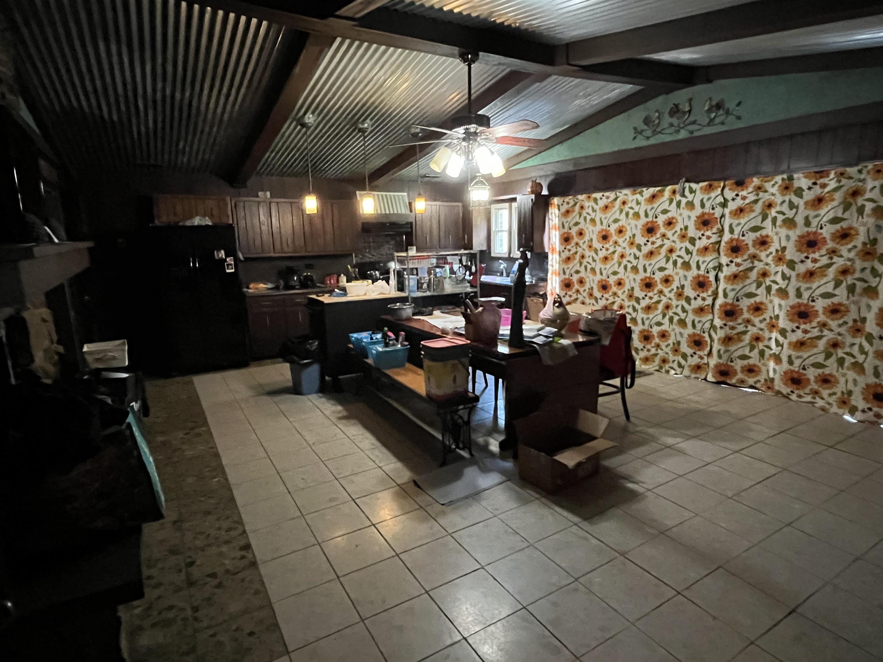 1125 Tyson Road Toone, TN 38381 - Photo 6 of 12 Spacious kitchen area featuring tile flooring, wooden cabinetry, exposed wood beams, and a corrugated metal ceiling